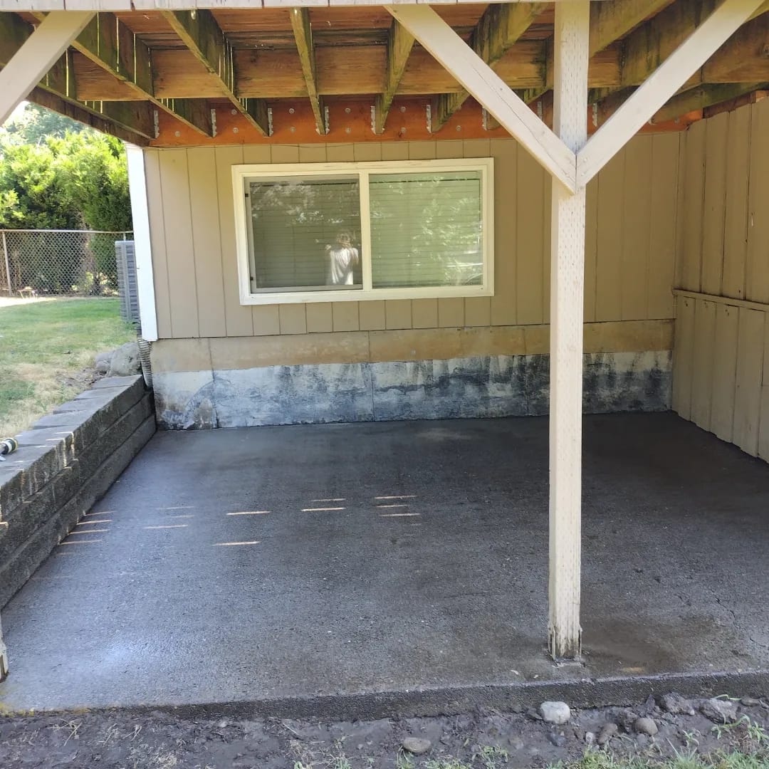 Carport slab and wall before a Curb Appeal power wash, grey and stained