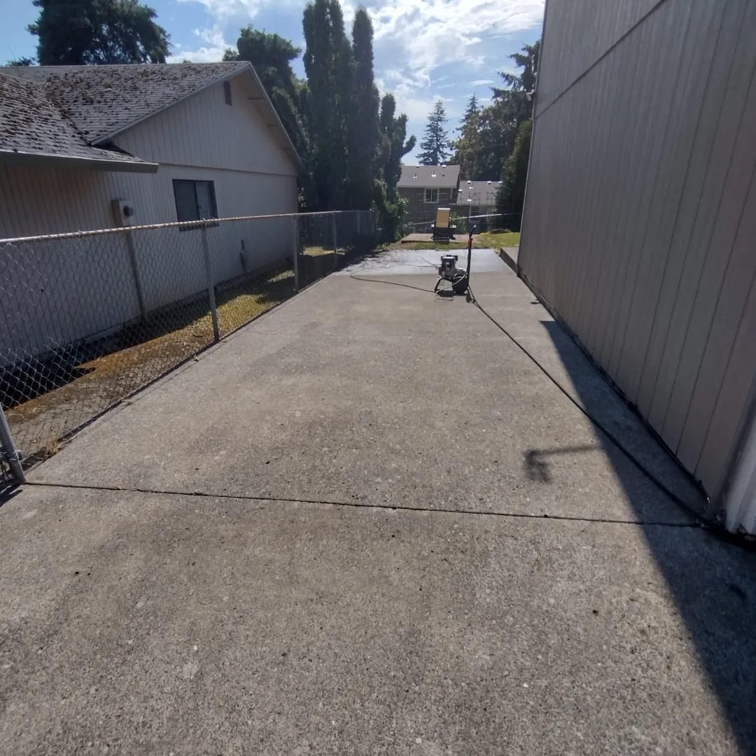 Concrete driveway after a Curb Appeal pressure wash, clean and dry beside a fence
