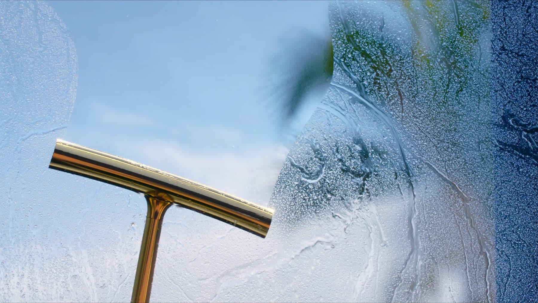 A squeegee pulling a sheet of water off exterior glass, the finish Curb Appeal window cleaning leaves behind